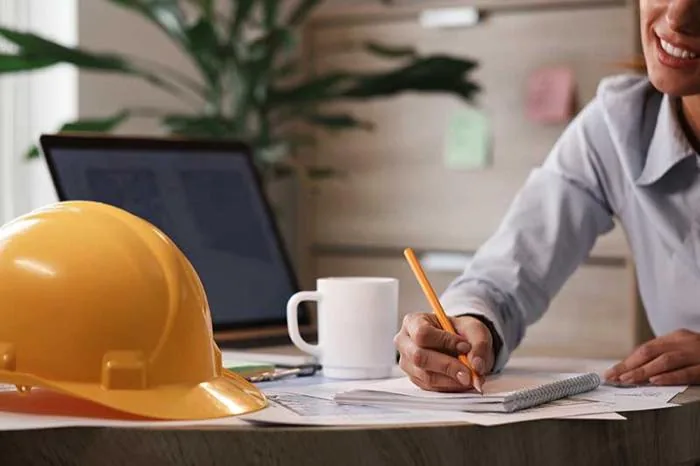Professionnelle au travail, casque de chantier posé sur le bureau