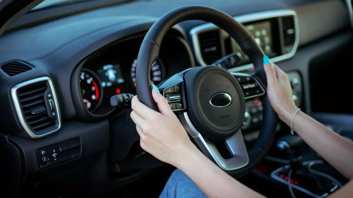 Jeune conductrice, les deux mains sur le volant, au poste de conduite d'une voiture.