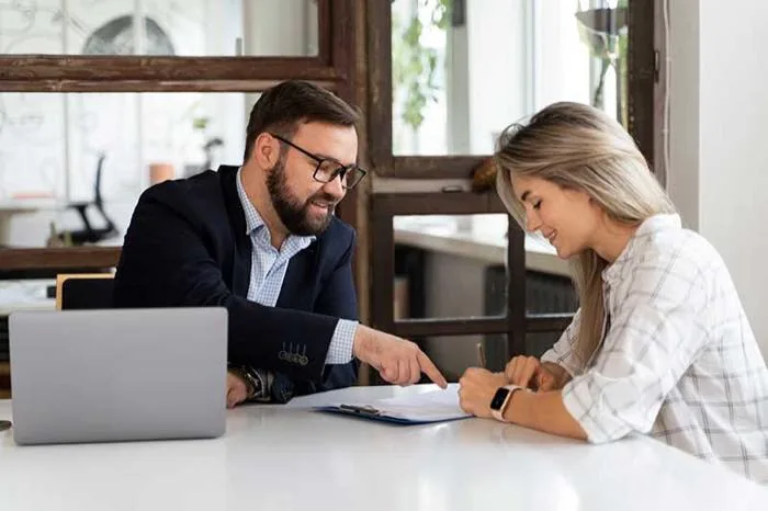 Un conseiller et une cliente devant un ordinateur portable